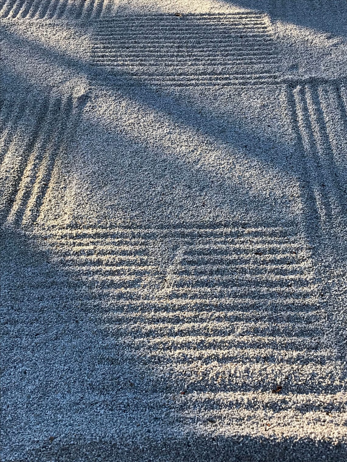 A Zen sand-garden—arranged in squares, some raked—transversed by light and shadows.