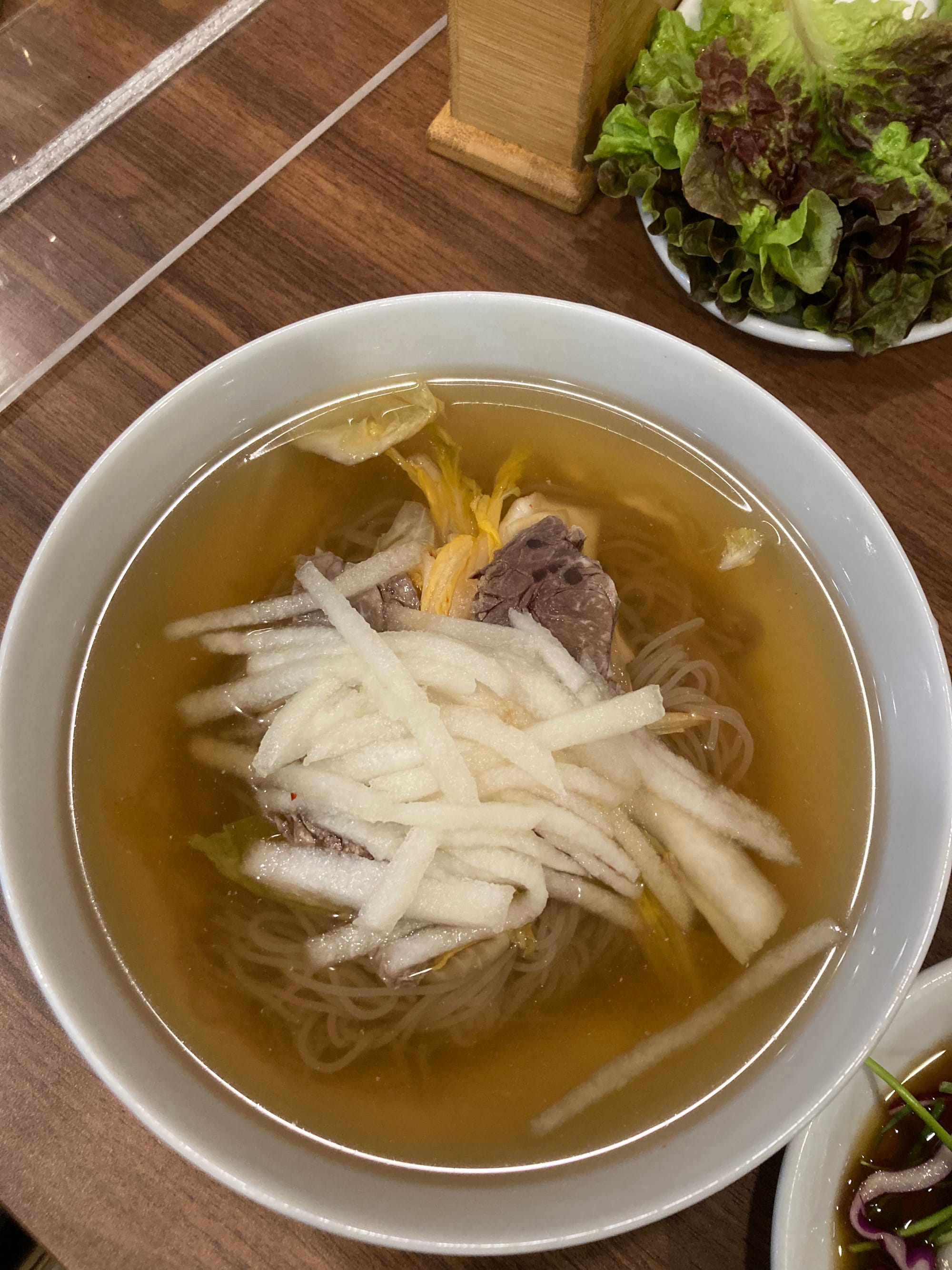 Close up of a bowl of cold noodles topped with slices of Asian pear.
