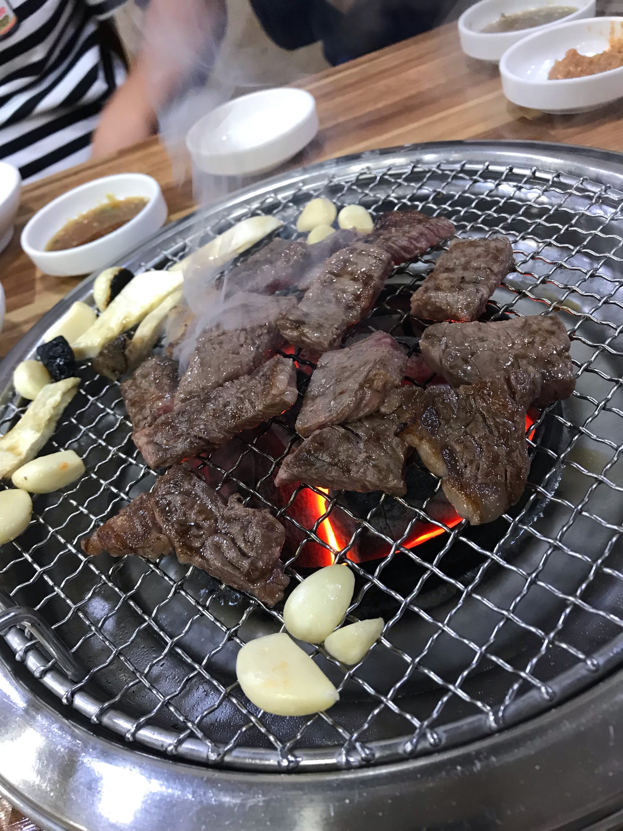 Bite-sized pieces of beef and garlic cloves on a Korean BBQ grill