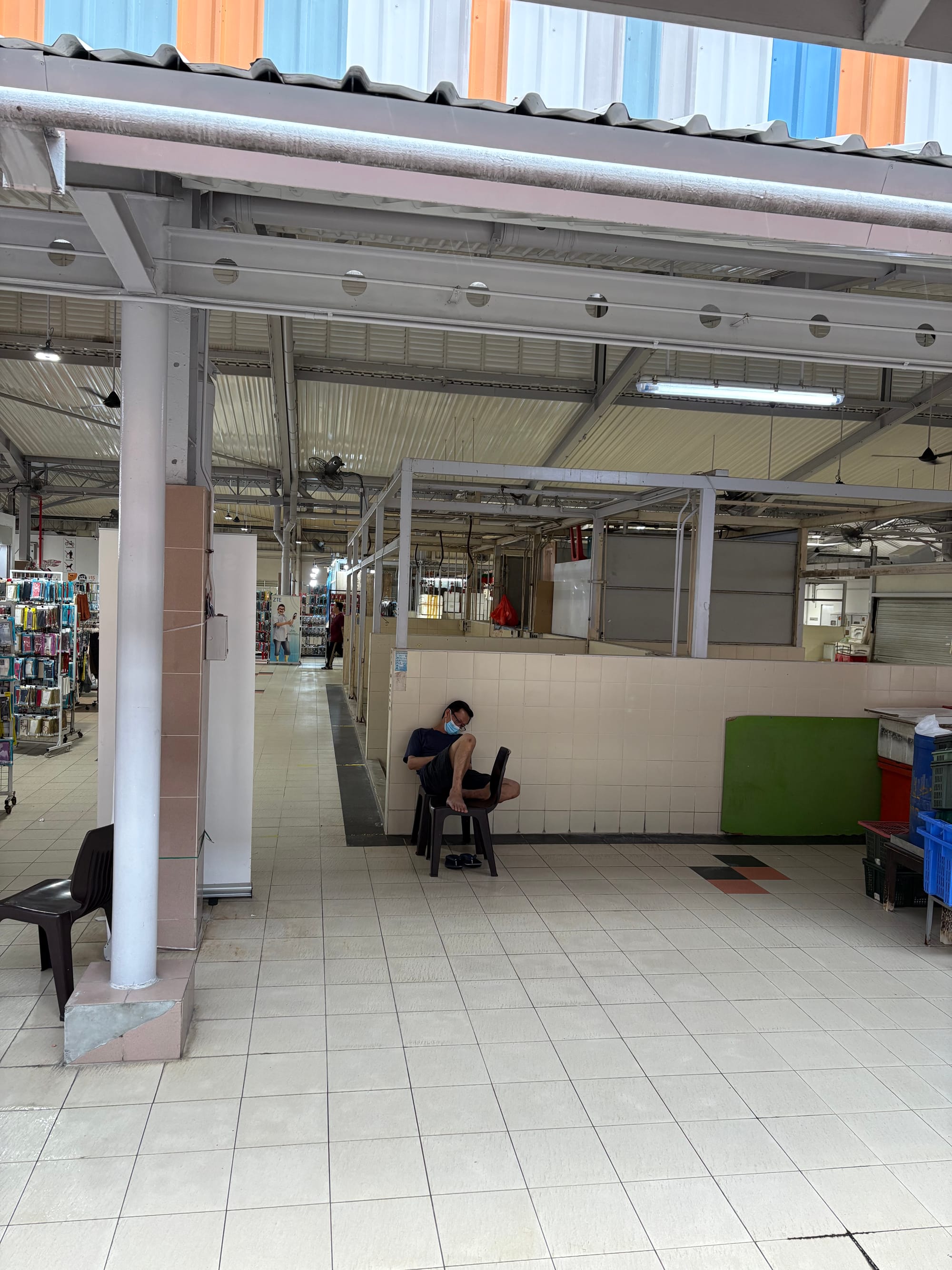 A man in a surgical mask takes a nap on two chairs.