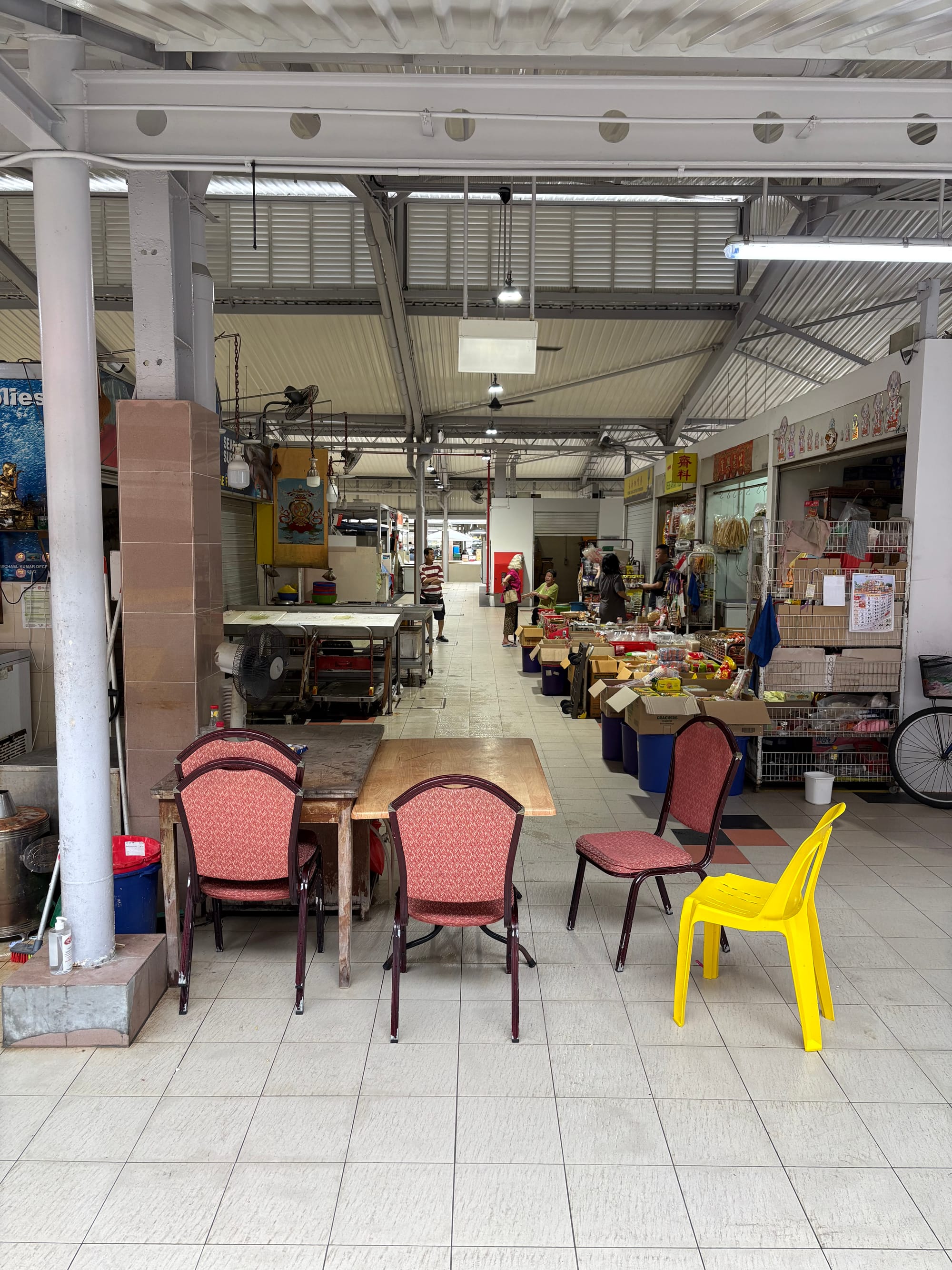 Chairs are scattered around a table. There are stalls in the background open. 