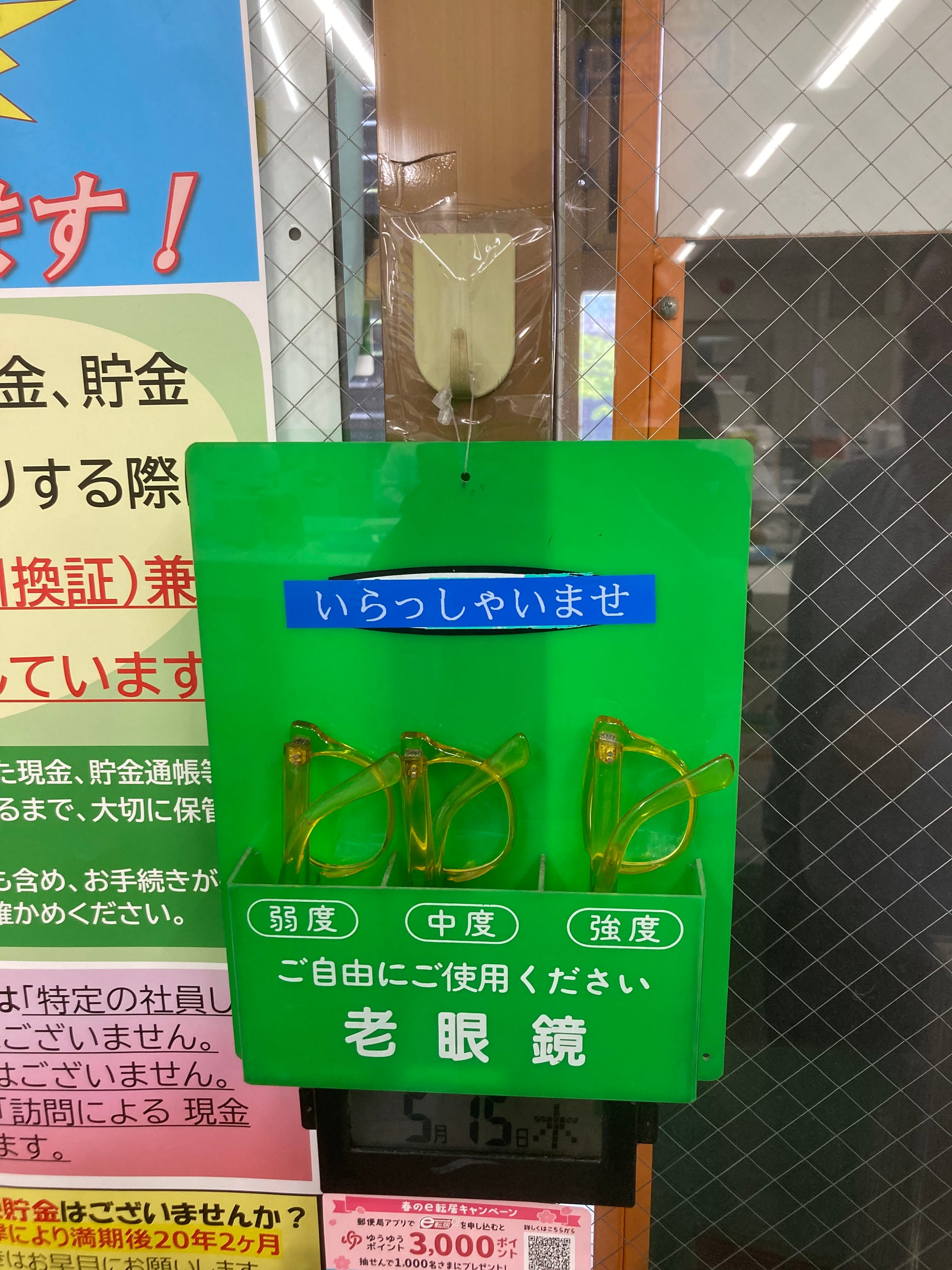 A green plastic holder contains 3 pairs of reading glasses of varying strength.