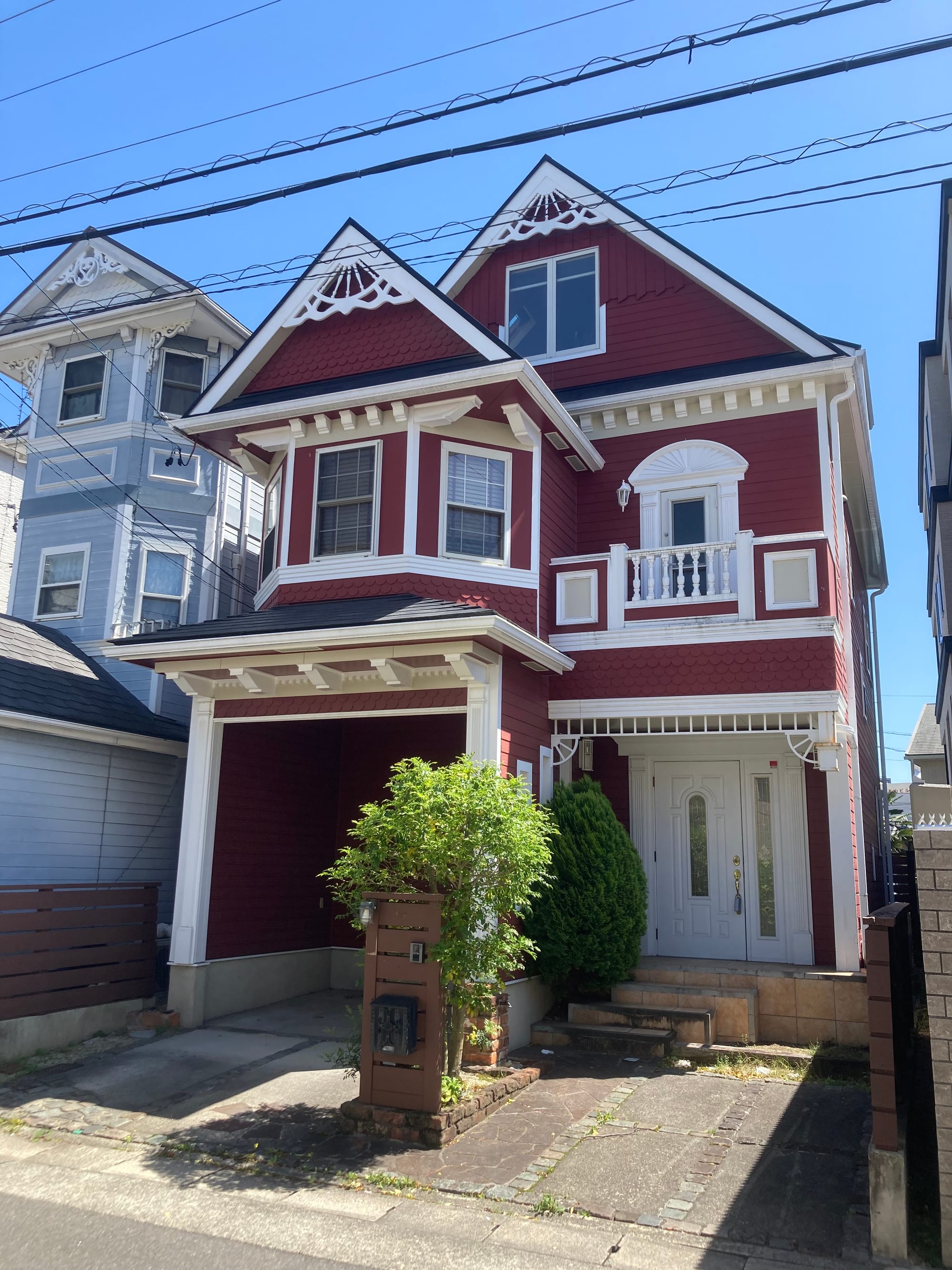 Two New England-style clapboard houses. The one on the left tis light blue and the other is a dark red with white trimmings.